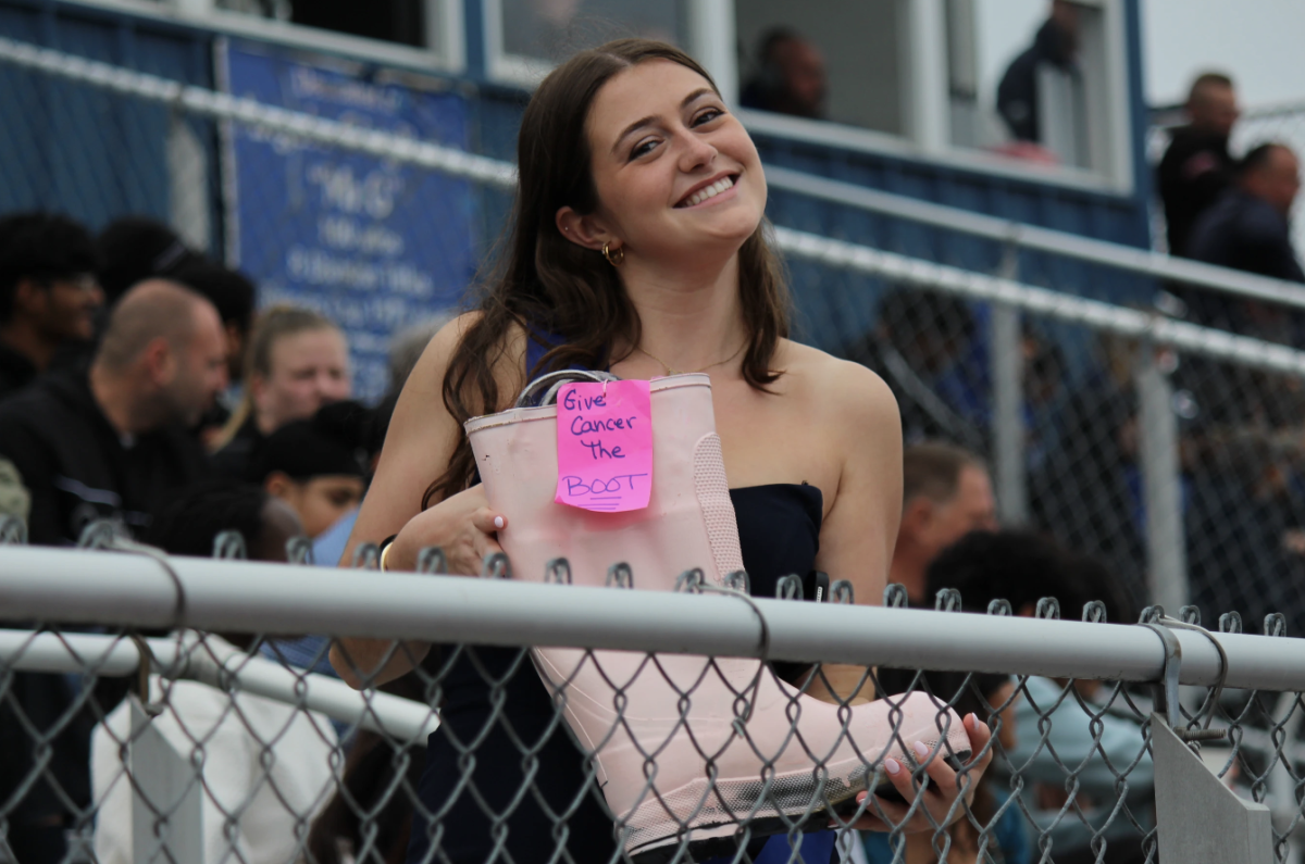 Senior Fiona O'Reilly passes the pink boot during the Homecoming football game.